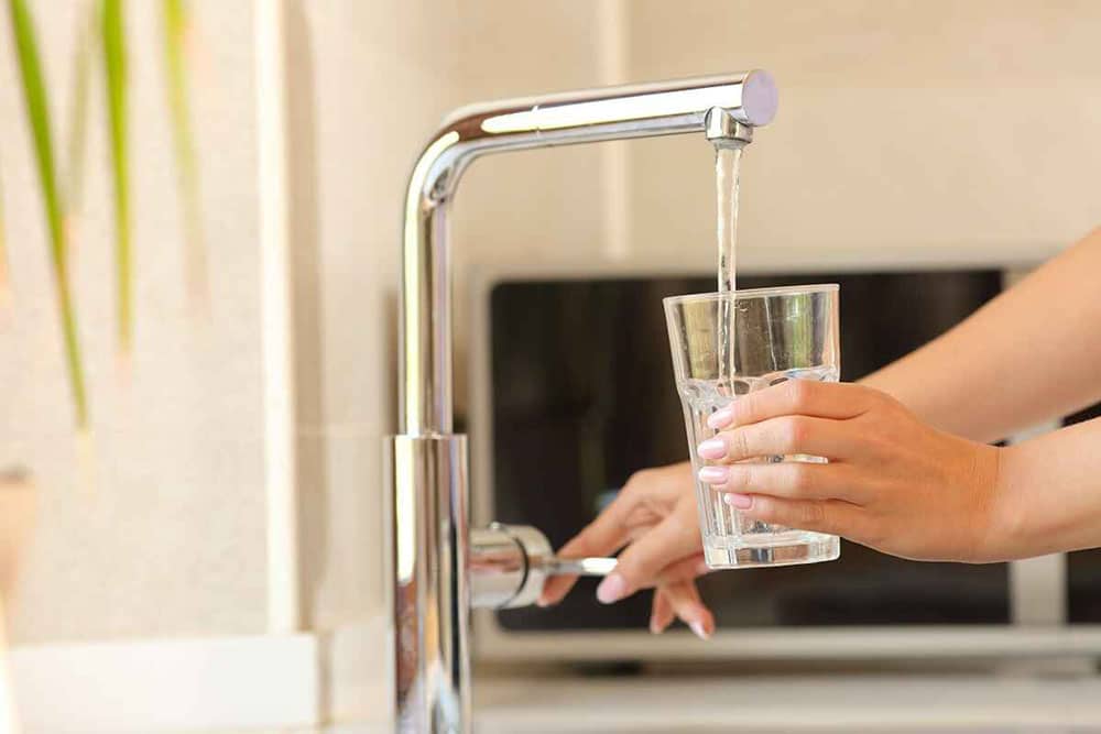 Drinking glass being filled with tap water