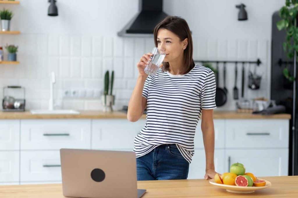 person drinking from a glass of water