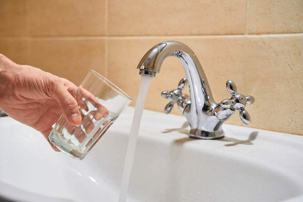 a hand holding a drinking glass under a running tap